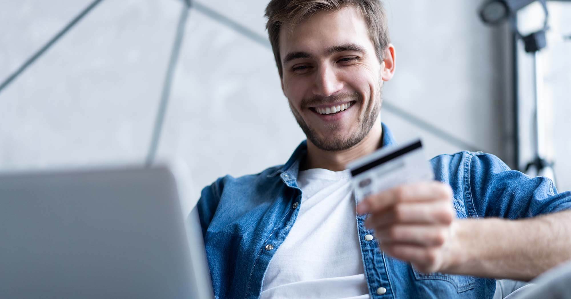 A man smiling as he researches credit union credit card rates in Utah online.