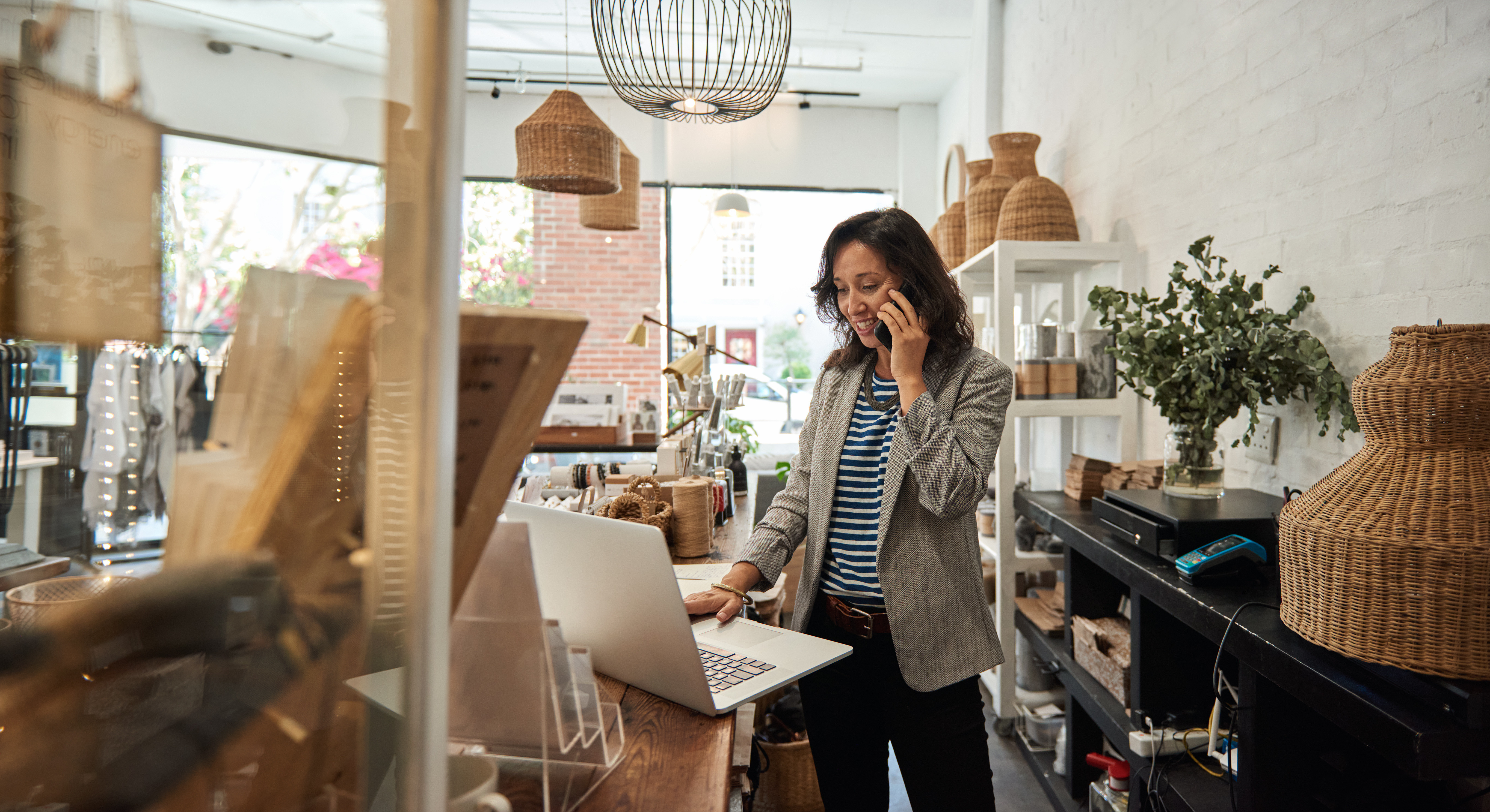 A business owner talks on the phone while simultaneously managing her business checking account online.